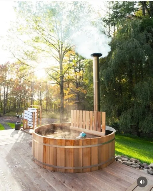 Cedar hot tub on custom deck with string lights at dusk — expansion into decking, 2015