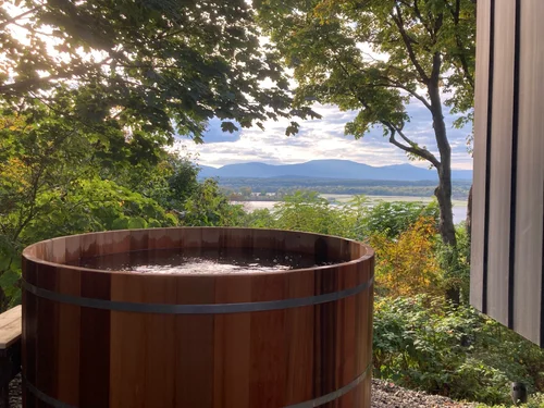 Cedar hot tub overlooking the Hudson Valley and Catskill Mountains — natural cedar tones against the landscape